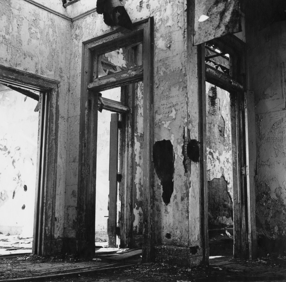Black-and-white photograph of the view of crumbling walls through four meeting derelict doorways