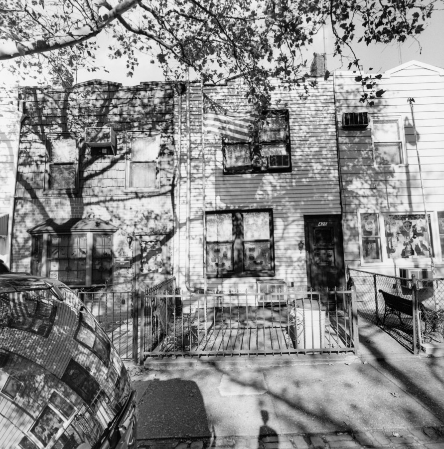A black and white photograph of row houses with shadows from trees