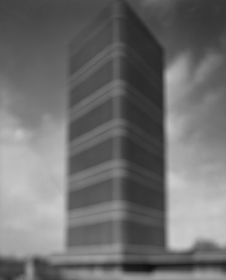 Black-and-white photograph of out of focus rectangular tower block building with rounded corners