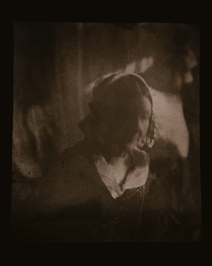 Brown-toned long-exposure photographic portrait of a woman with a blurred face and centrally-parted hair