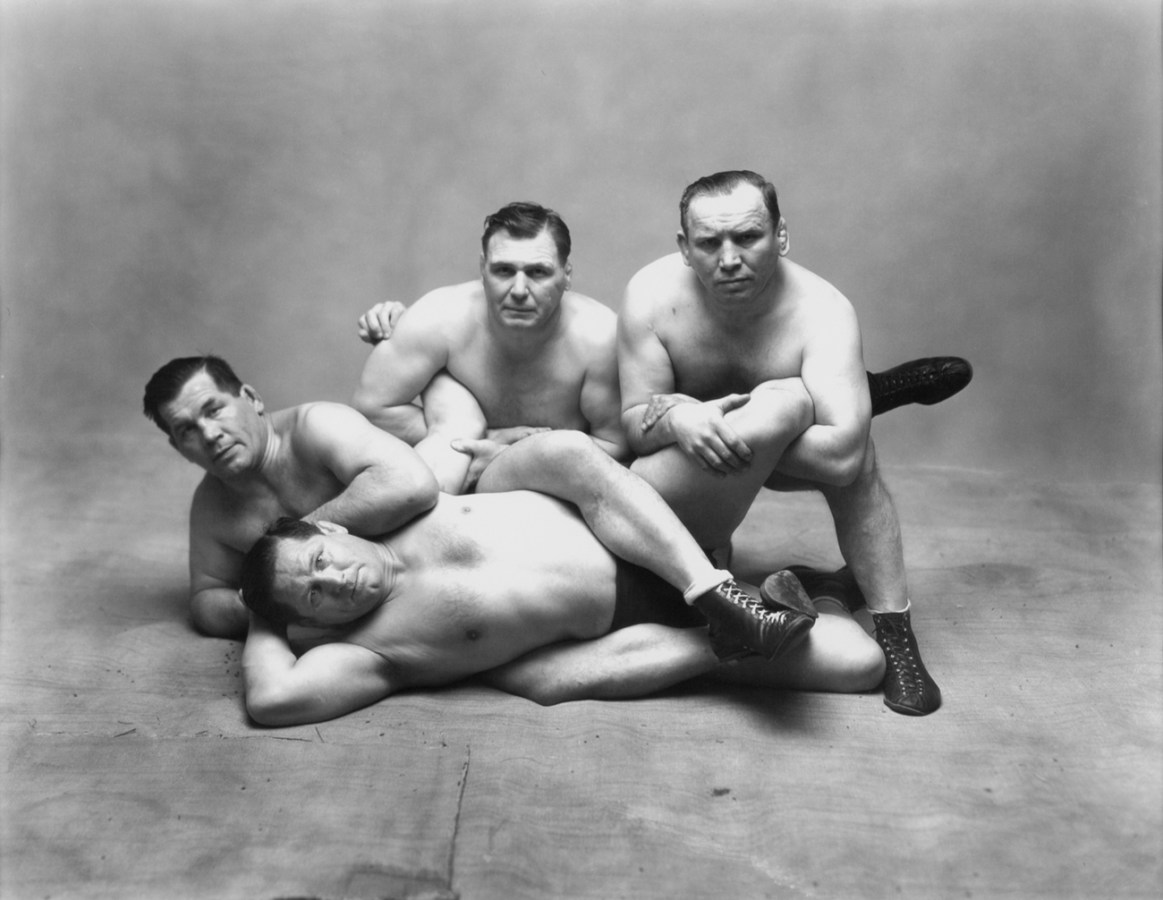 Black-and-white photograph of four wrestlers posing in crouched or laying positions