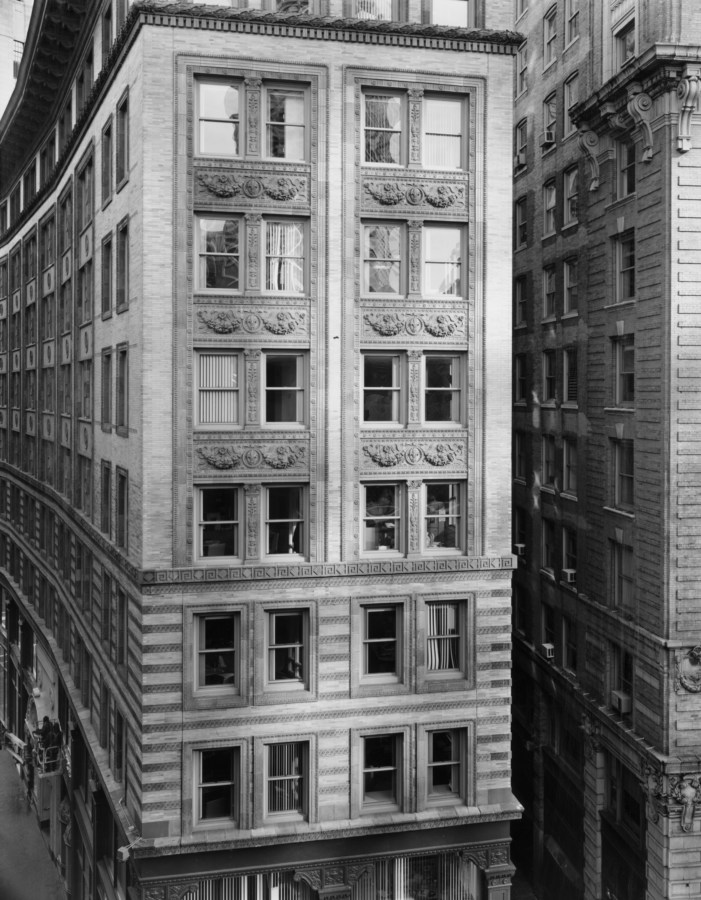 Black-and-white frontal photograph of an eight-story building receding into the distance