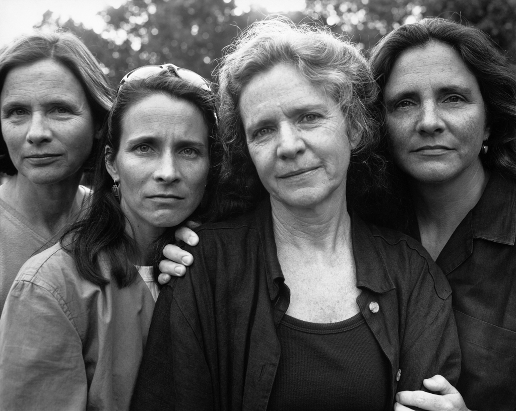 Black-and-white photographic portrait of four women standing outside