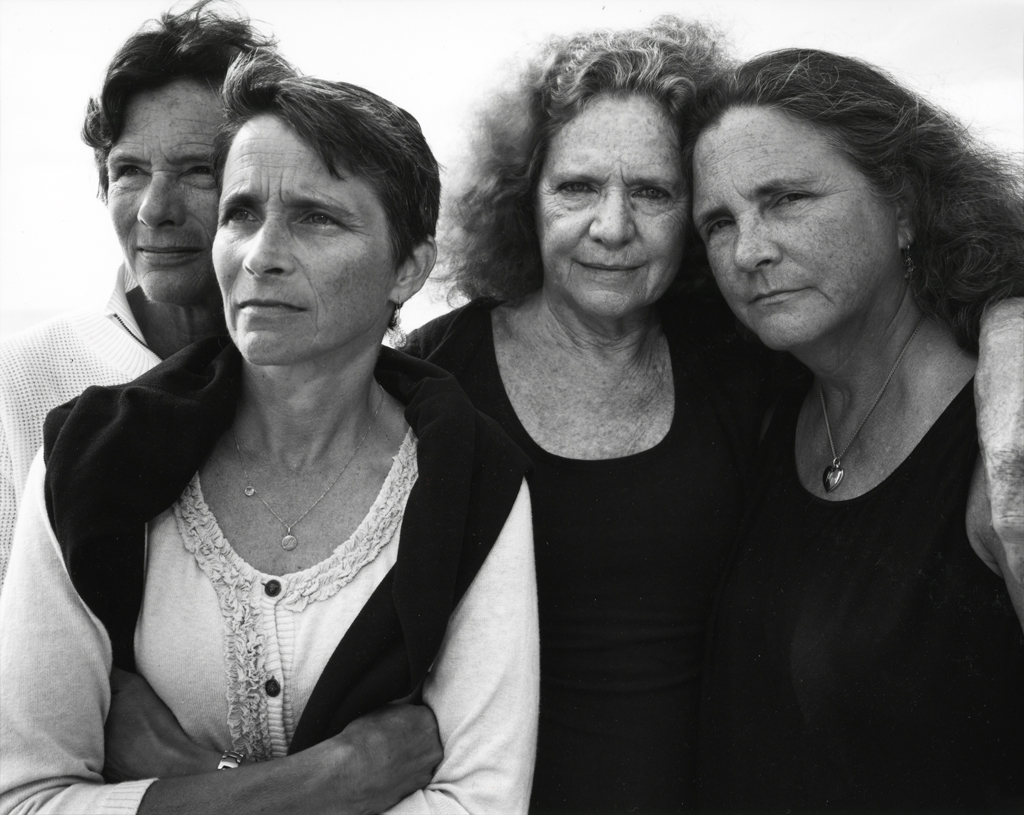 Black-and-white photographic portrait of four middle-aged women with two looking into the distance and two looking at the viewer