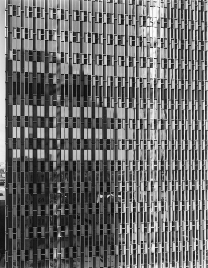 Black-and-white photograph of the glass-windowed façade of a modern office building