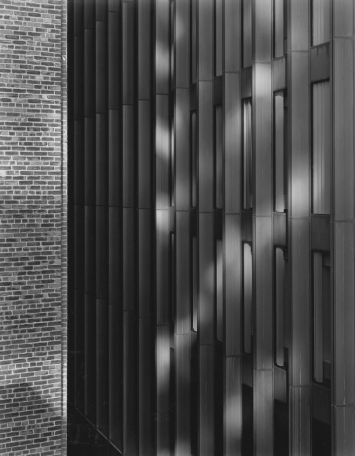 Black-and-white photograph of reflected light and shadow on a modern high-rise building façade