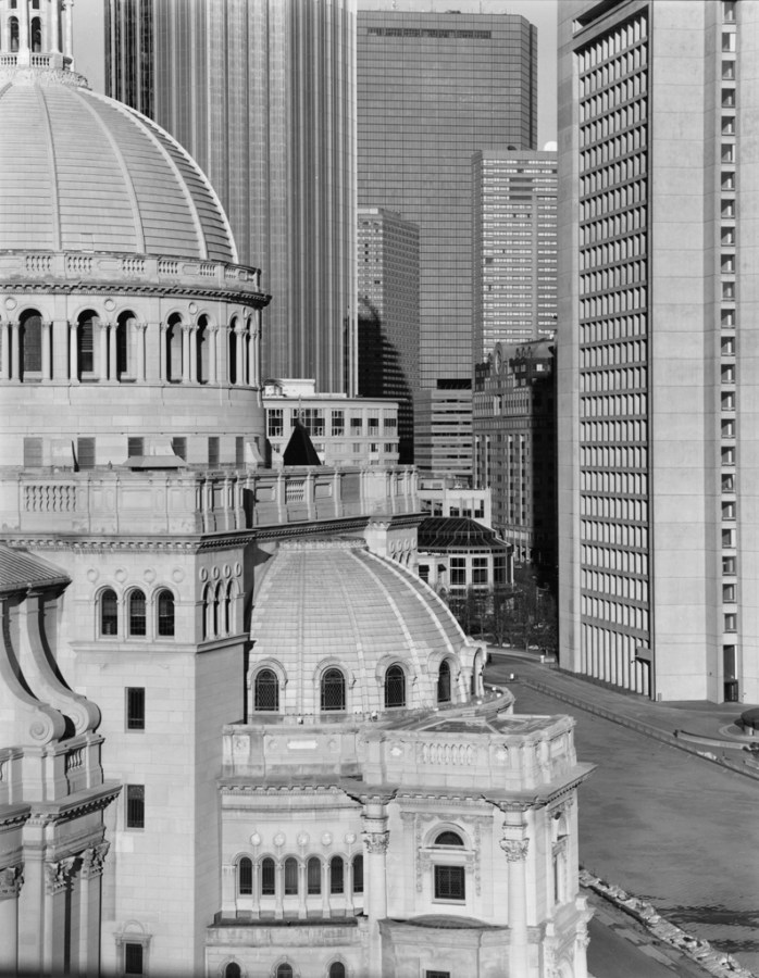 Black-and-white photograph of a domed church building against a background of modern high-rise building