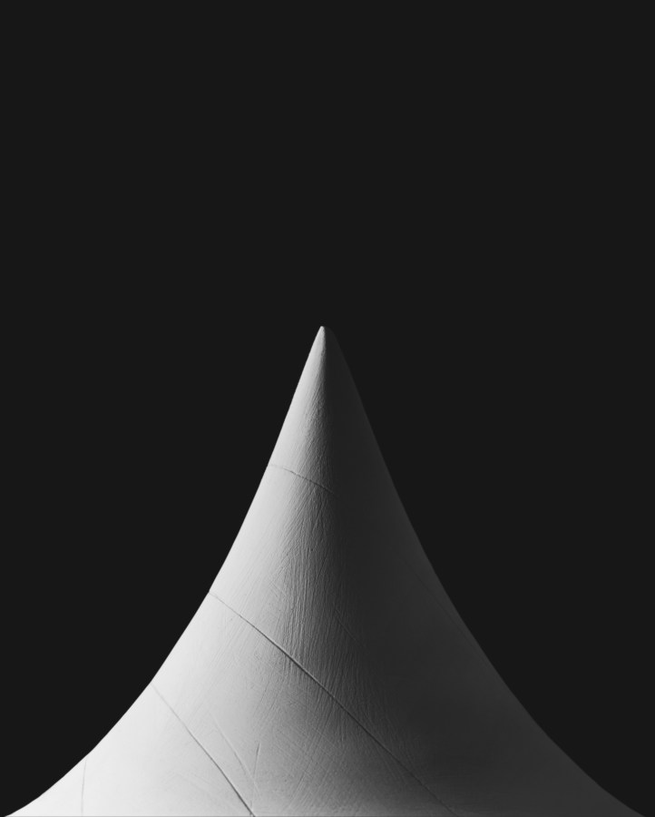 A black and white photograph of a conical shape, starkly lit