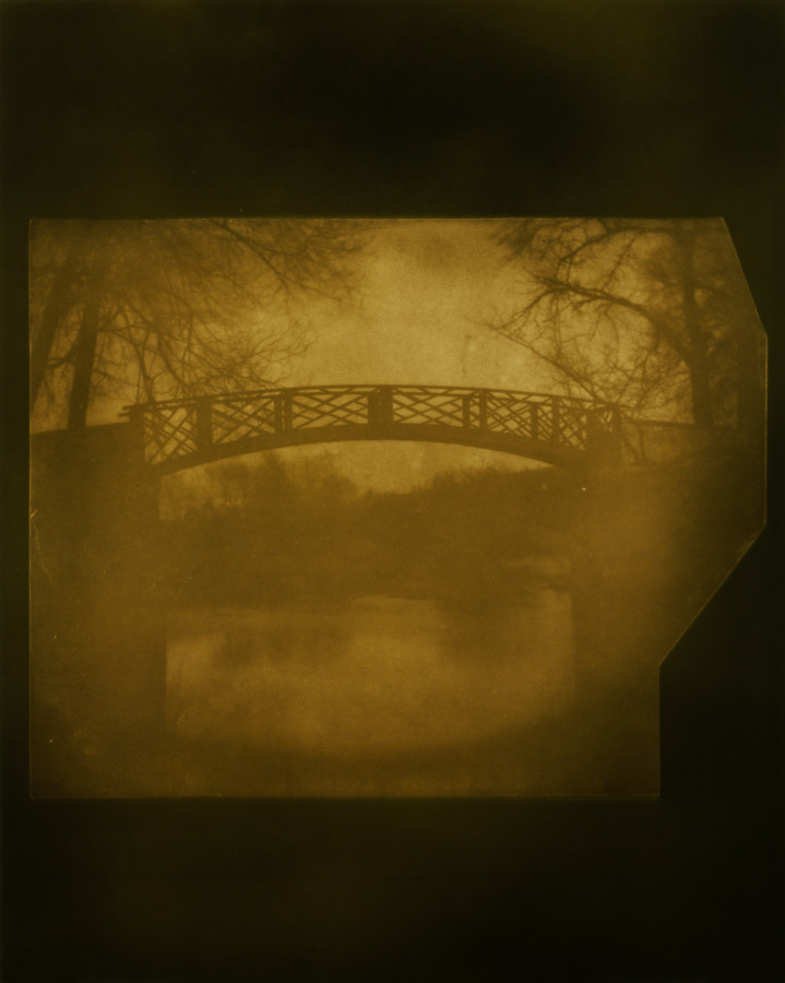 Yellow-toned photograph of a foot-bridge under bare trees