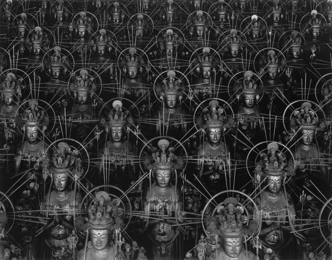Black-and-white photograph of receding rows of Buddha statues arranged in an alternating pattern