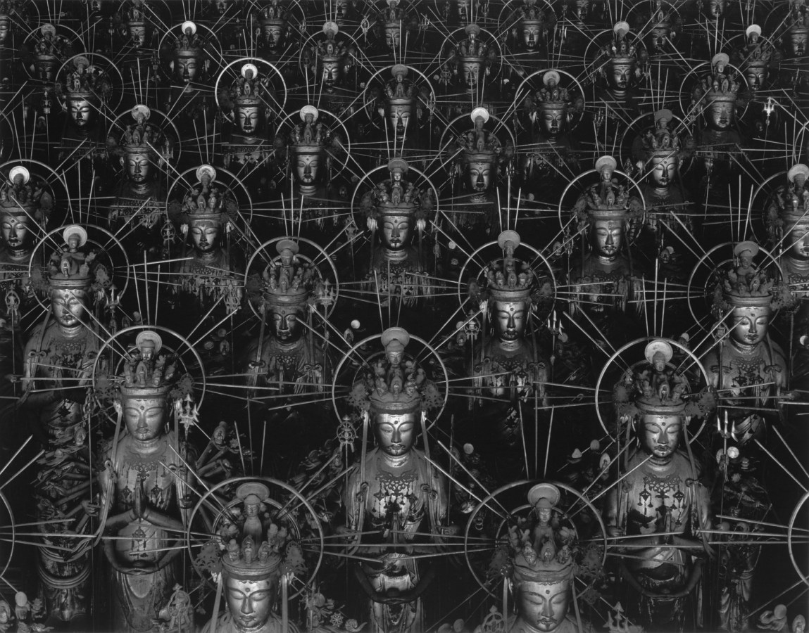 Black-and-white photograph of receding rows of Buddha statues arranged in an alternating pattern