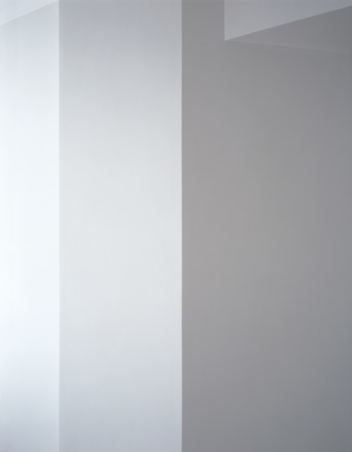 Photograph of a white wall with ceiling beam in varying shades of light gray