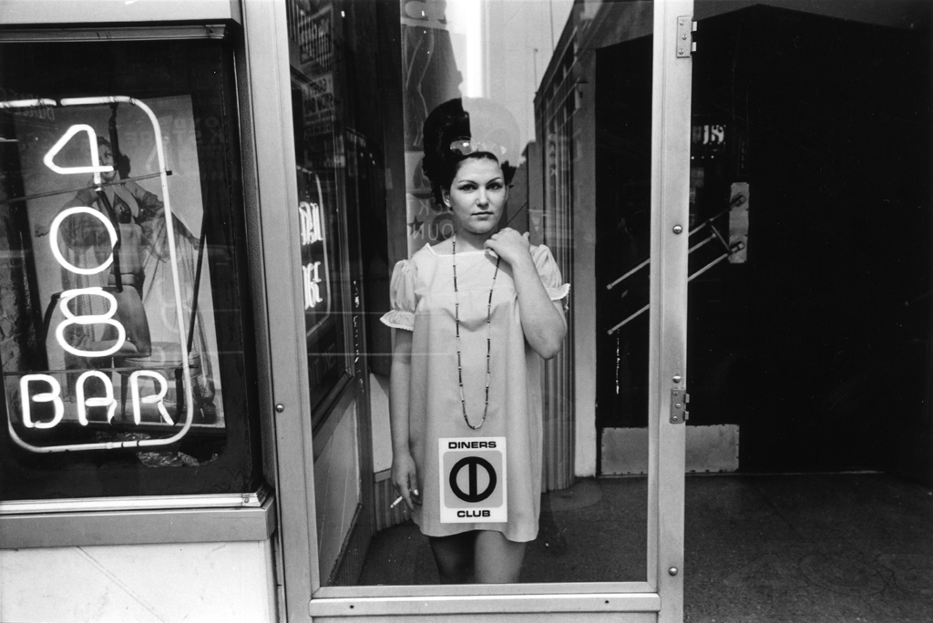 Black-and-white photograph of a woman standing behind a glass door
