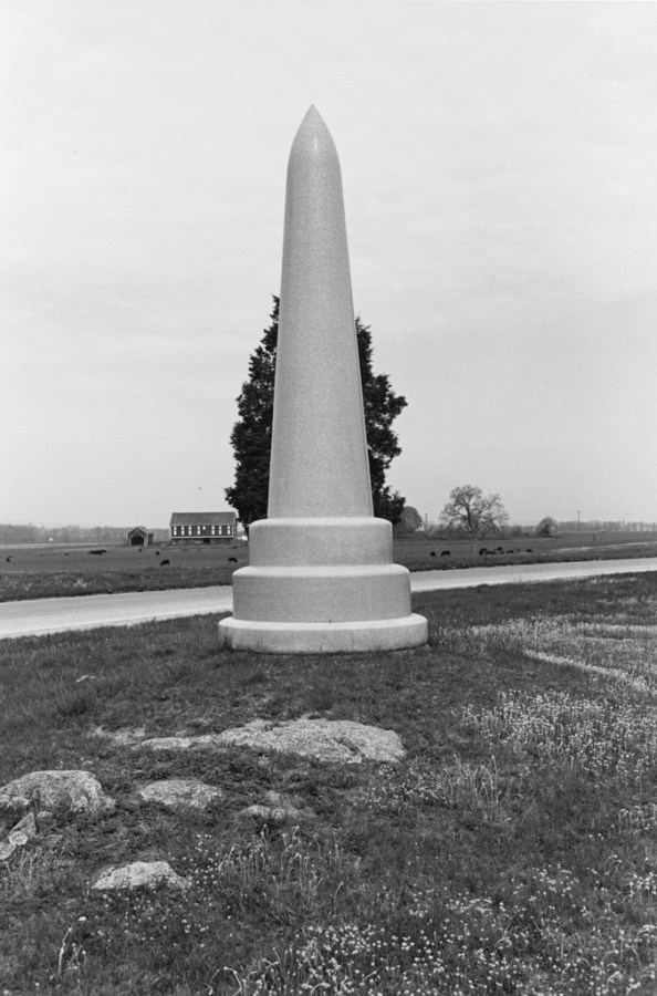 Black and white photograph of a monument with a tree directly behind it