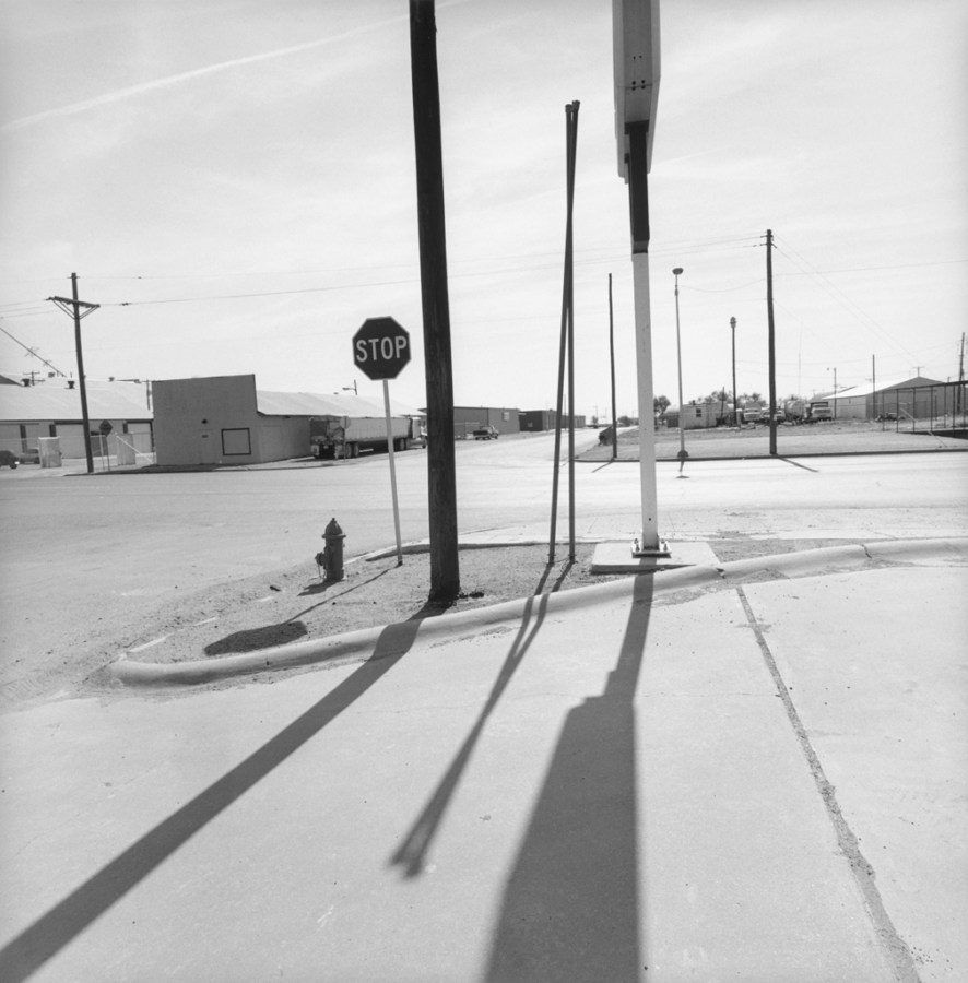 A black and white photograph of roadside signs and their shadows