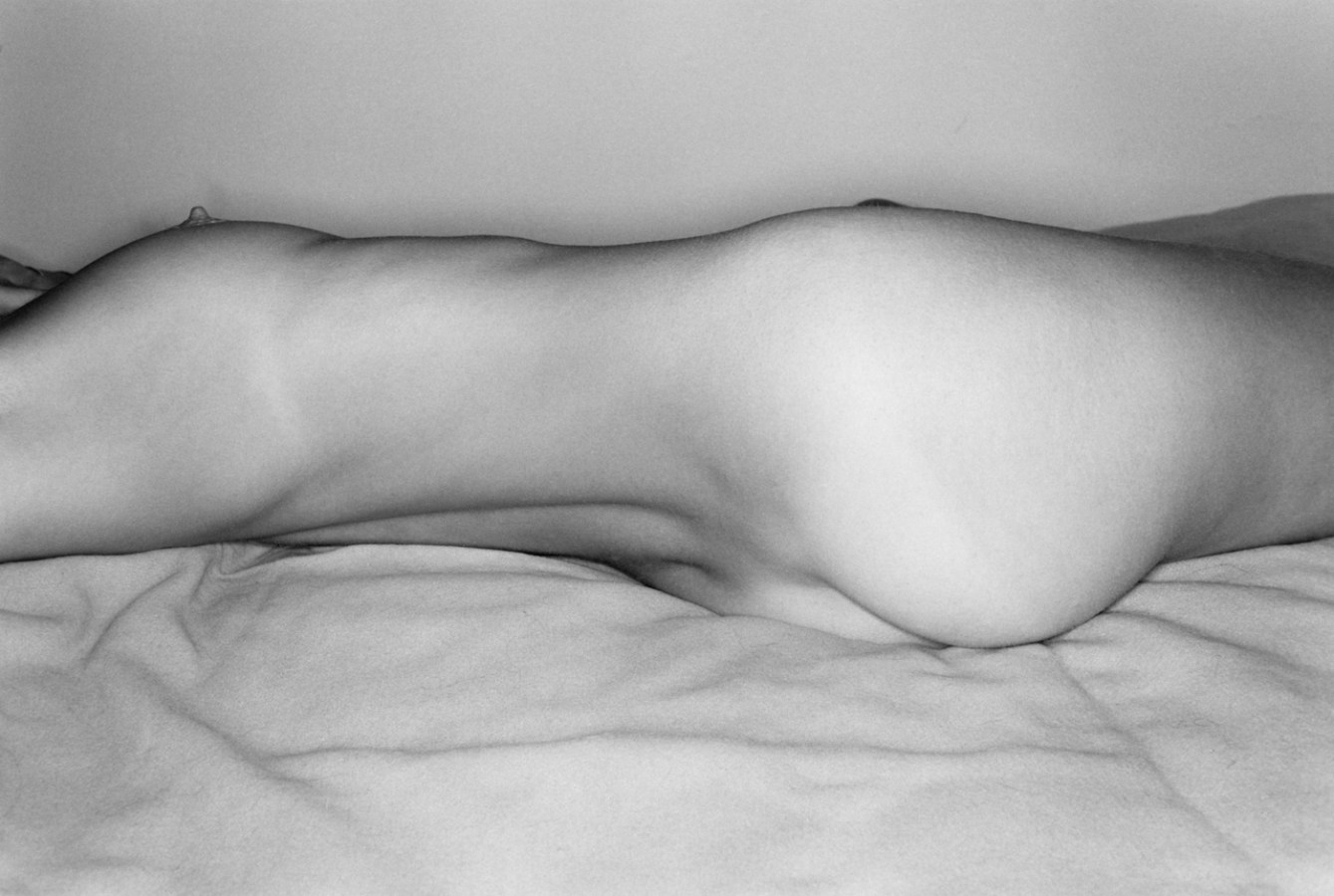 A black and white photograph of a nude woman's torso