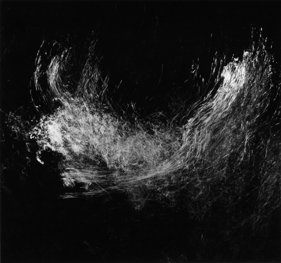 Square black-and-white long-exposure photograph of light reflecting off of splashing water