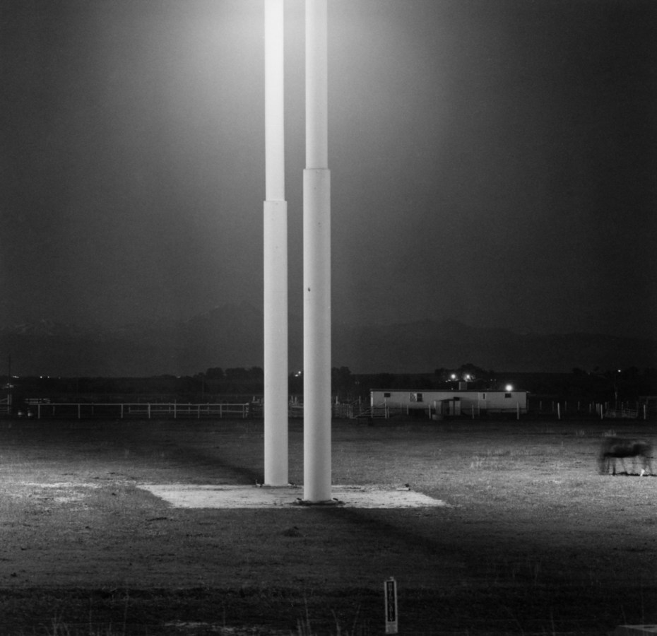 Black-and-white photograph of two illuminated metal poles at night