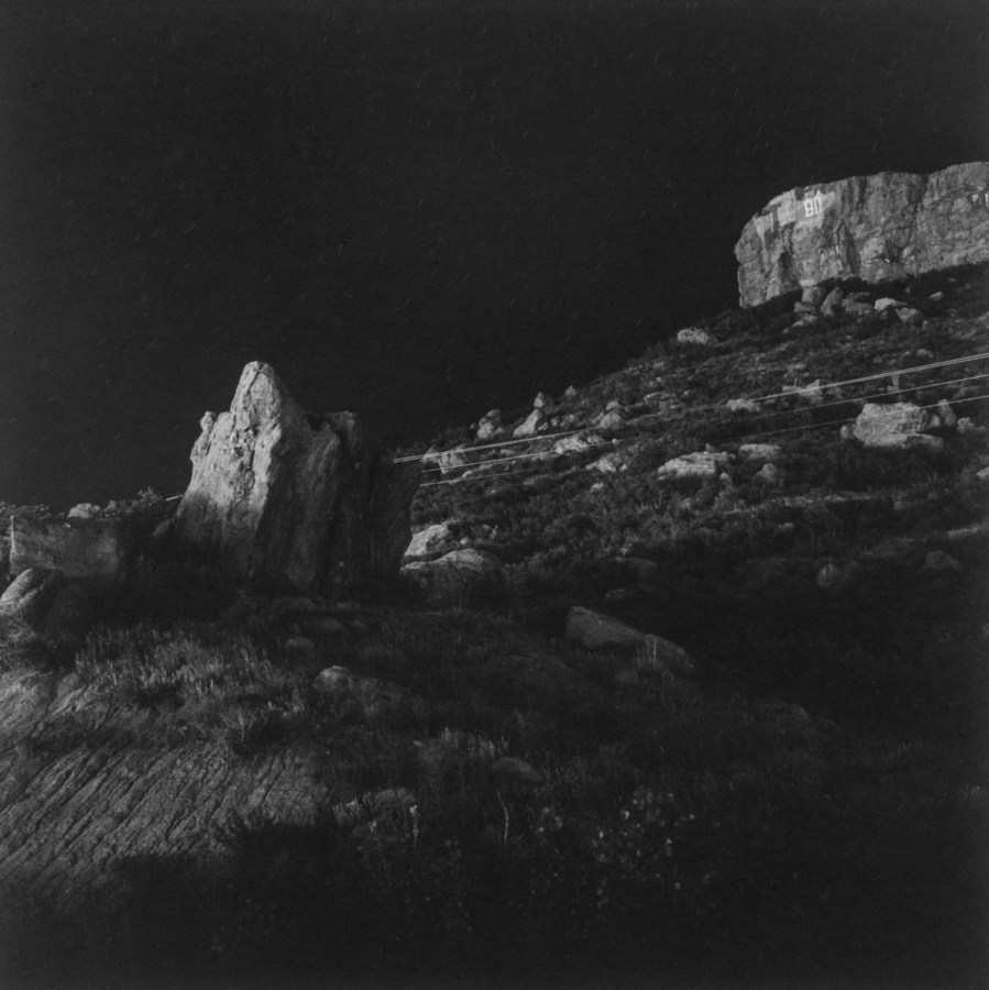 Black-and-white photograph of rock formations and telephone lines at night