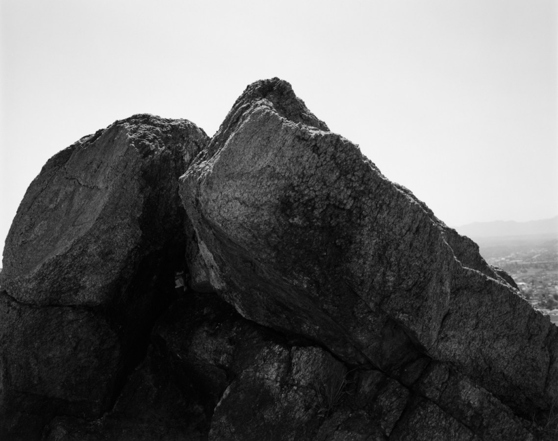 Black-and-white photograph of a rock formation against a bright clear sky