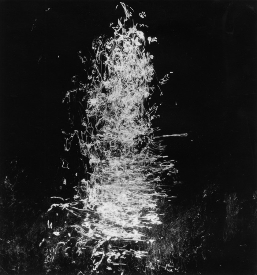Square black-and-white long-exposure photograph of light trails reflecting off of moving water
