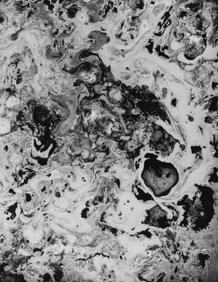 Black-and-white close-up photograph of a foaming, marble-textured liquid surface