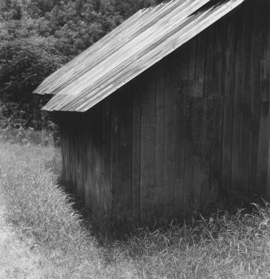 Black-and-white multiple-exposure photograph of the corner of a wooden shed with sloping roof