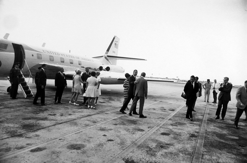 Black-and-white photograph of a small group disembarking from a United States jet on the runway
