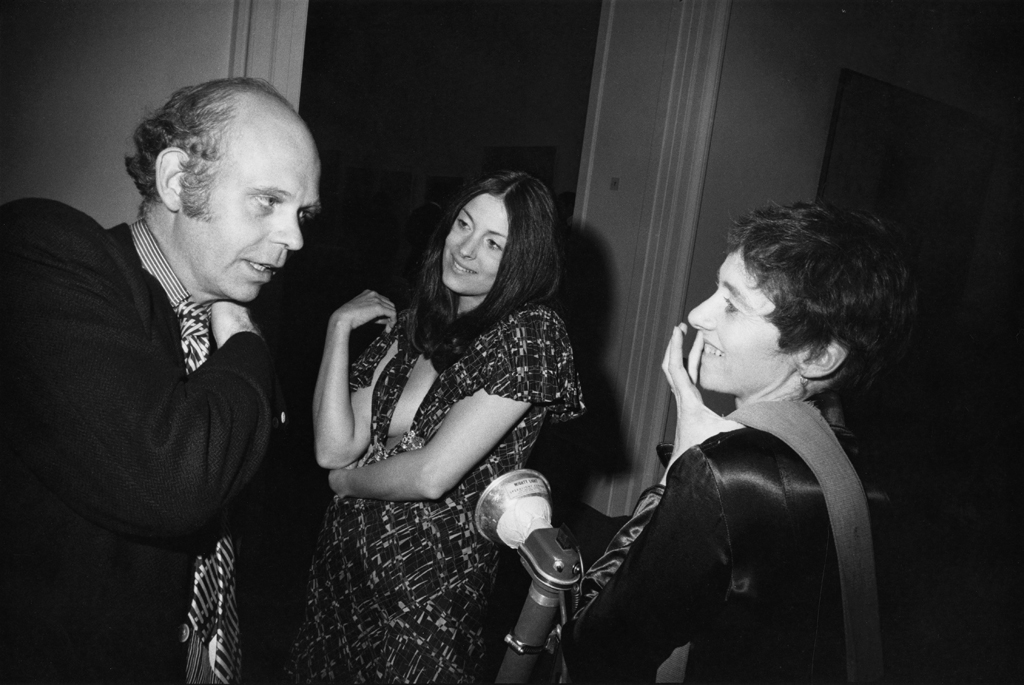 Black-and-white photograph of a man speaking to two smiling women