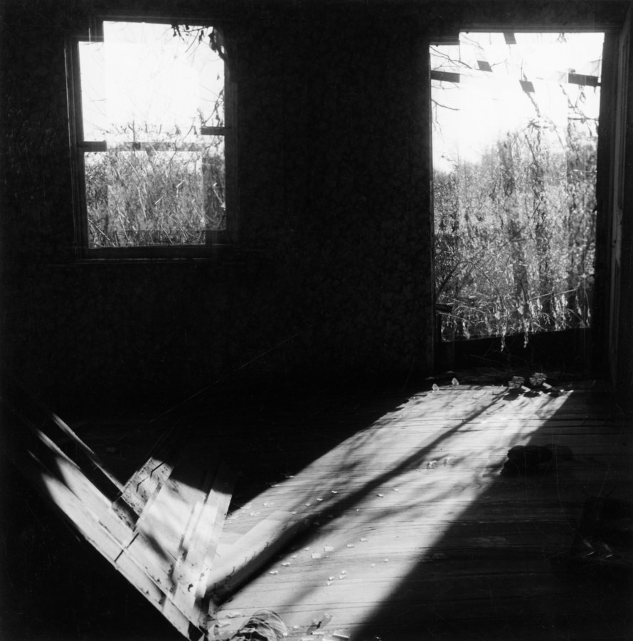 Black-and-white multiple-exposure photograph of sunlight entering a dark room through two windows