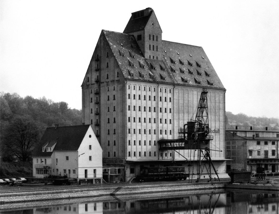 Black and white photograph of a large industrial building alongside a canal