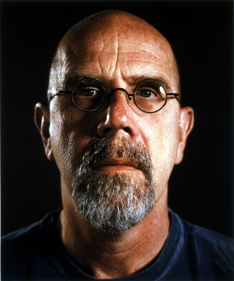 Color portrait photograph of a bald man with a greying beard and round glasses