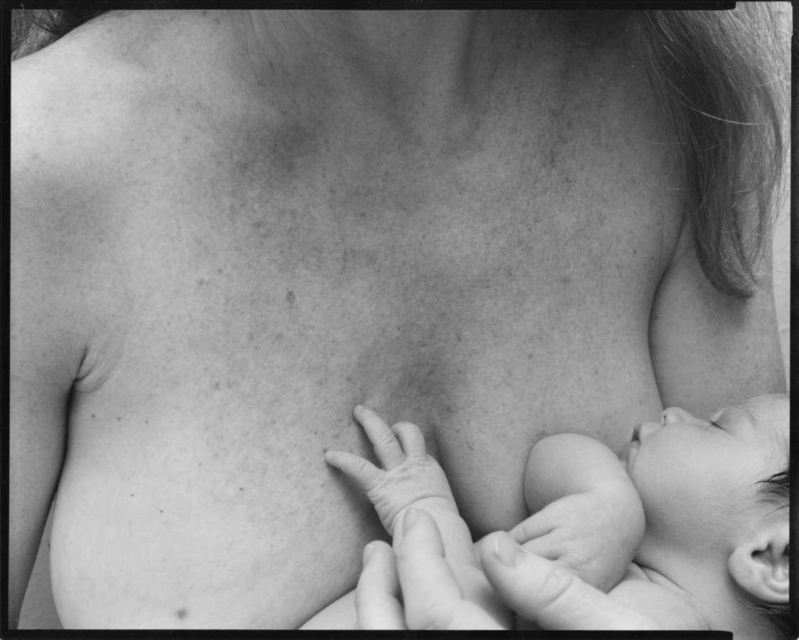 Black and white photograph of a baby asleep against a woman's bare chest