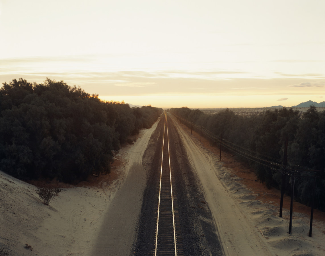 Color photograph of train tracks receding into the horizon.