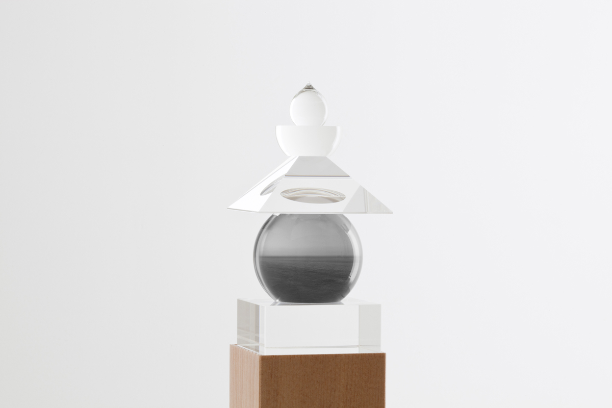 Glass sculpture of stacked geometric shapes with a black-and-white photo of a seascape inserted in the central orb