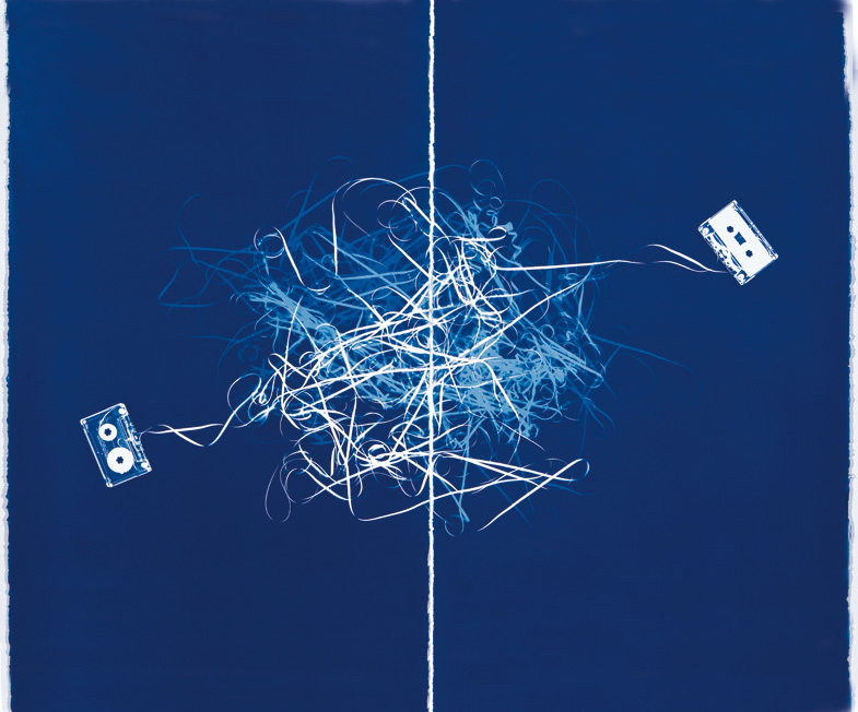 Horizontal image of the white tapes of two cassettes tangling in the middle on a deep blue background