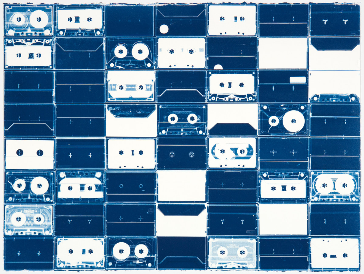 Horizontal image of a grid of white cassette tapes and their outlines on a background of deep blue