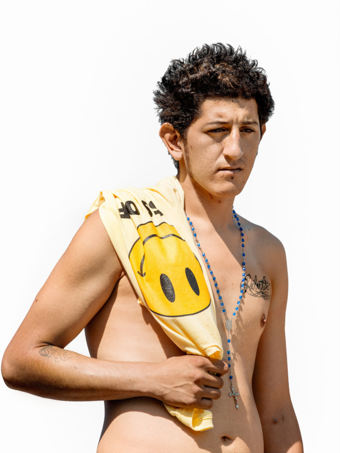 Color photographic portrait of a shirtless young man holding a t-shirt over his shoulder