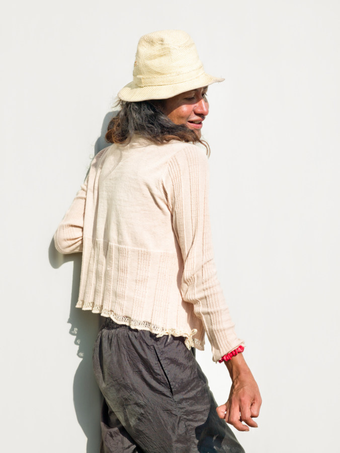 Color photograph of a woman in a white top and hat with her head turned back over her shoulder