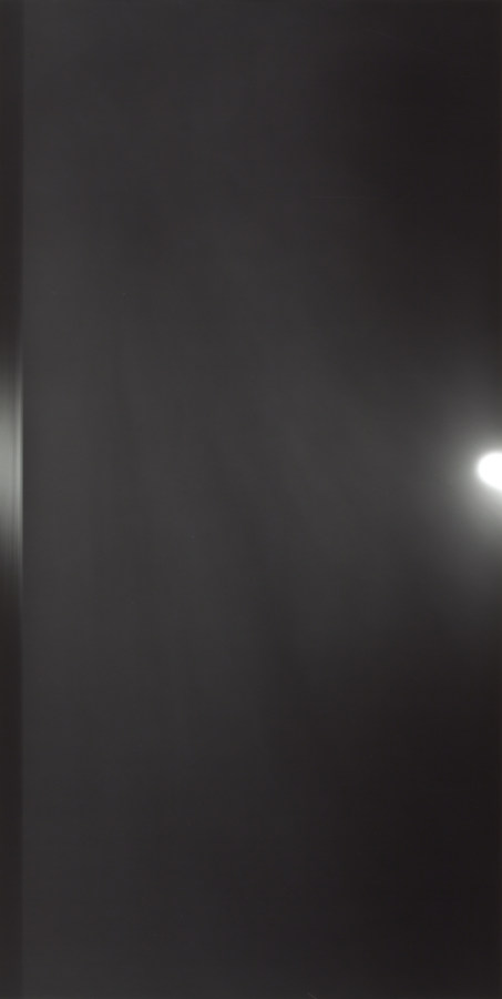 Black-and-white vertical photograph of a horizontal black seascape under a round white sun
