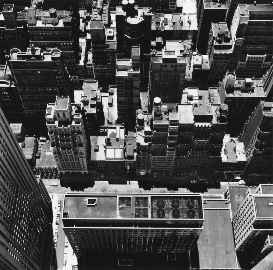 Black-and-white photograph of city buildings and rooftops from a higher vantage point