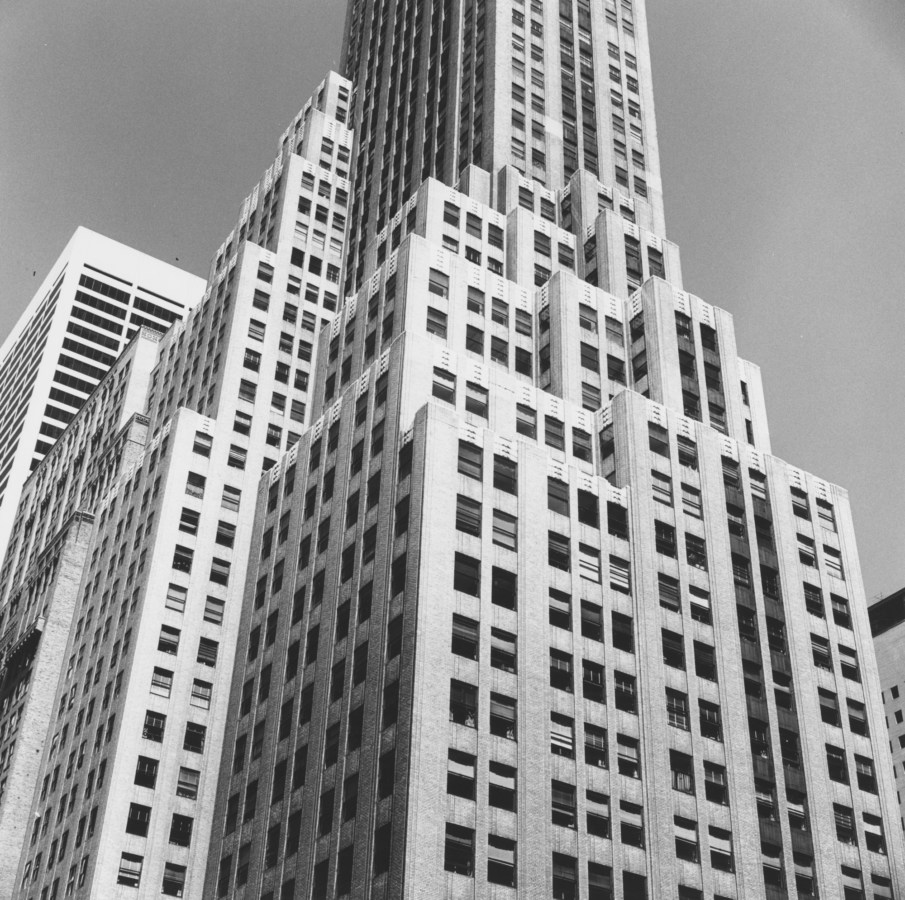 Black-and-white photograph of a stepped high-rise building from below