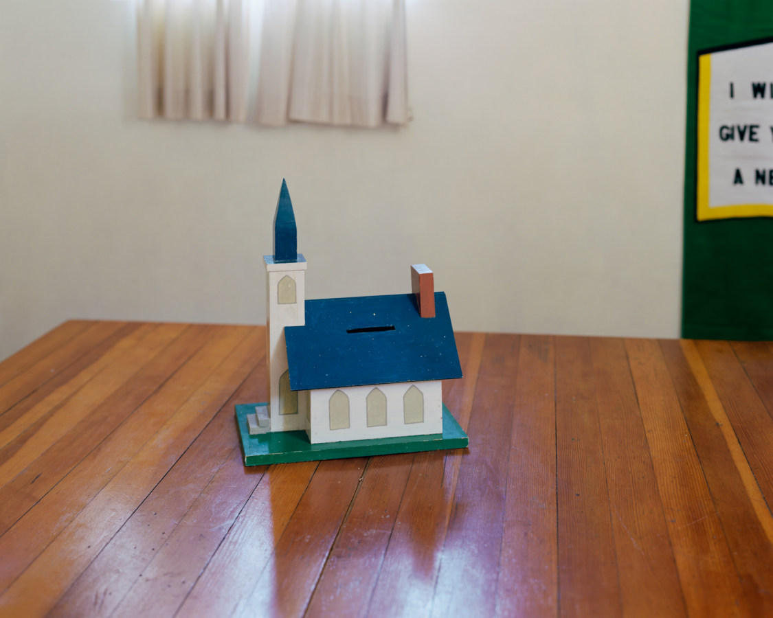 Color photograph of a simple model of a church sitting on a wooden table