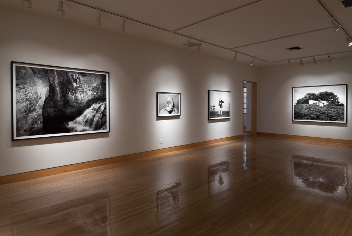 Color photograph of black and white photographs on white gallery wall