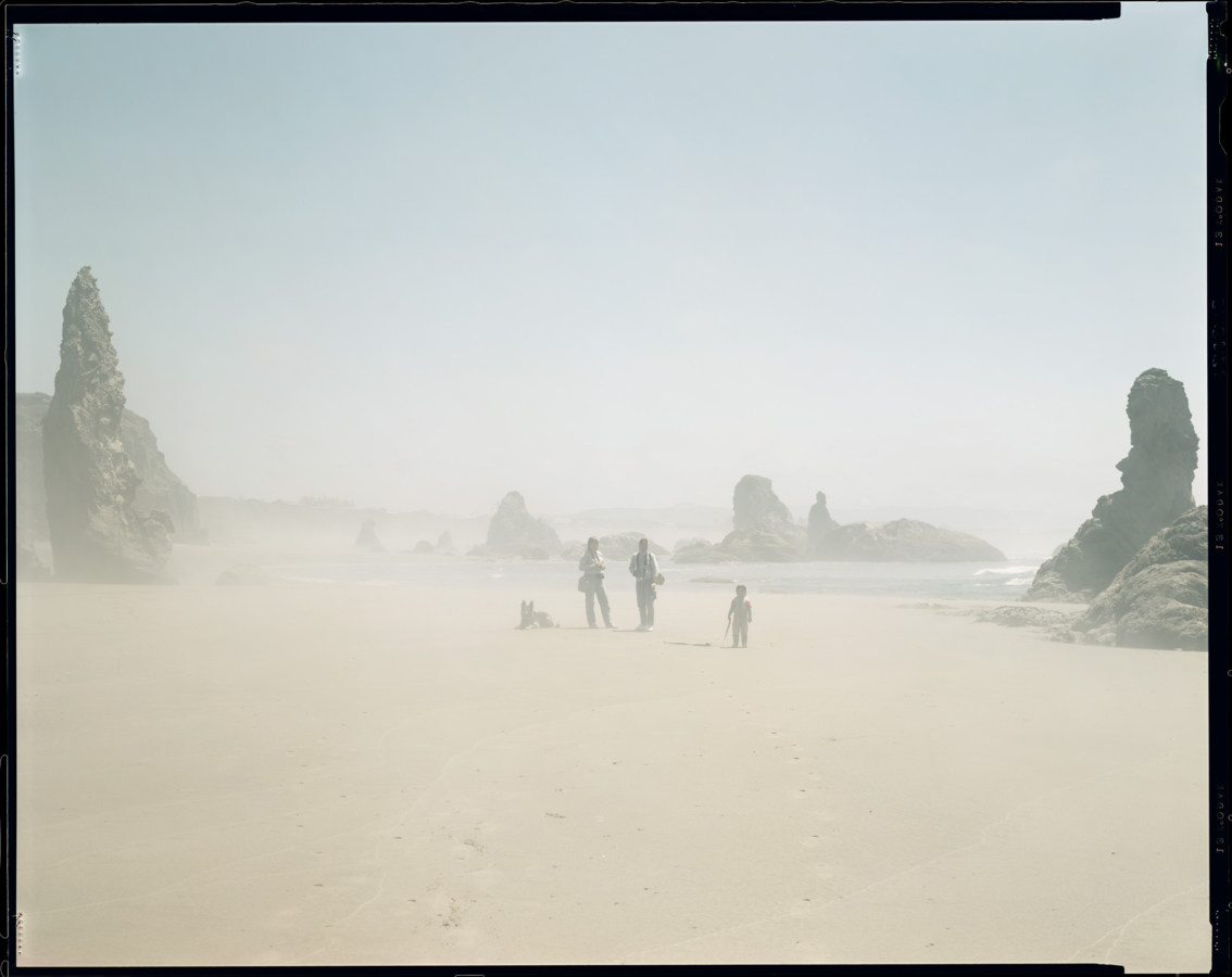 Color photograph of three people and one dog on the Oregon coast