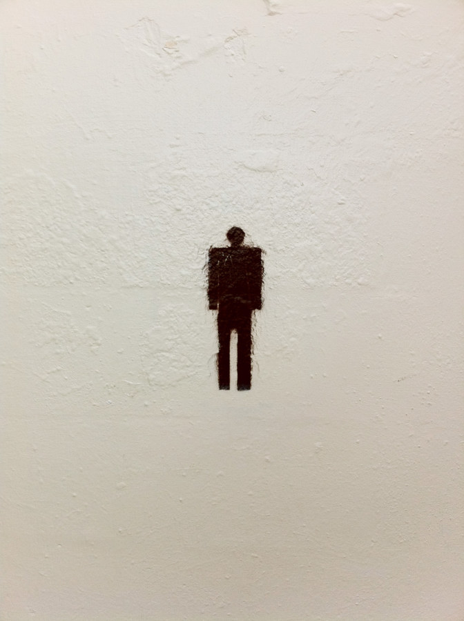 Color photograph of wall with black painted figure of a person