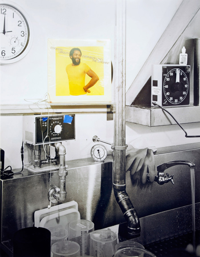 Color photograph of a black and white photo development space with color vinyl sleeve of 'Everybody loves the sunshine' by Roy Ayers