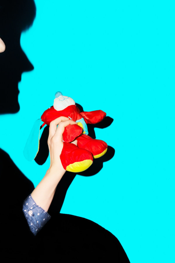 Color photograph of a silhouetted figure holding a red stuffed animal