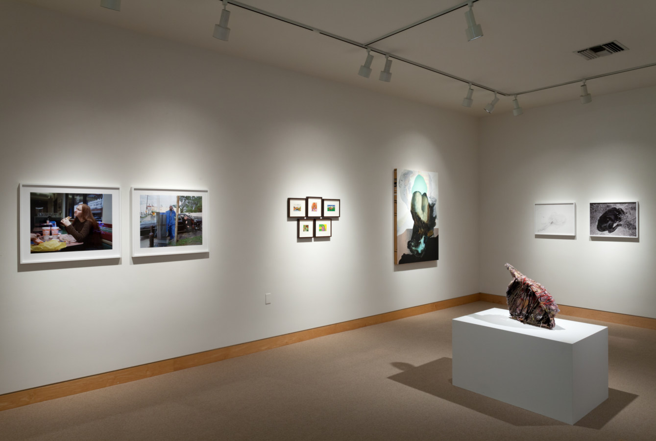 Color image of exhibition depicting artworks both framed and sculptural within gallery
