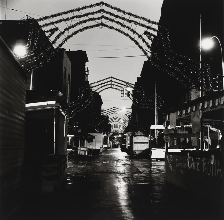 Black-and-white photograph of an empty street with marquees and tinsel arches spanning the road